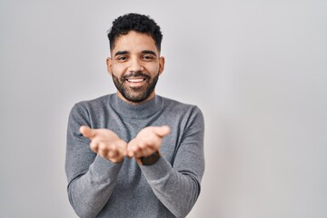 Hispanic man with beard standing over white background smiling with hands palms together receiving or giving gesture. hold and protection