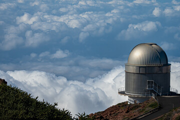 Fototapeta premium Large telescope at summit of mountain above the clouds 