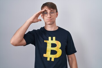 Caucasian blond man wearing bitcoin t shirt worried and stressed about a problem with hand on...