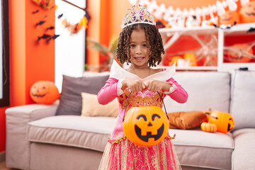 African american girl wearing princess costume holding pumpkin basket at home