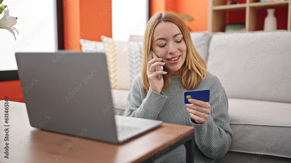 Poster Young blonde woman talking on smartphone holding credit card sitting on sofa at home