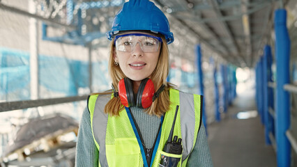 Young blonde woman builder smiling confident standing at street