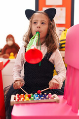 Adorable hispanic girl playing xylophone and trumpet at kindergarten