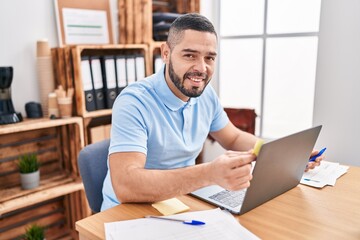 Young latin man business worker using laptop and smartphone at office