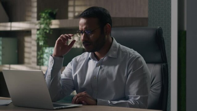 Concerned Indian man American businessman at table take off glasses thinking problem solution pensive sad laptop read unpleasant news bad e-mail computer failure financial bankruptcy crisis in office