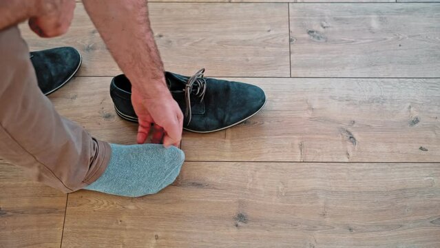 Embarrassed Caucasian Male Taking Off Shoes Discovering Hole in His Sock