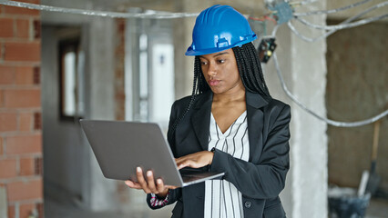 African american woman architect using laptop at construction site