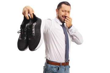 Man holding a pair of stinky trainers - obrazy, fototapety, plakaty