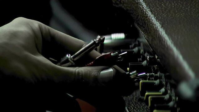 Man Hand Plugging an Instrument Cable into a Guitar Amplifier. Close Up.