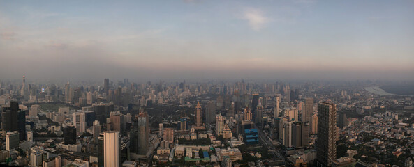 Twilight panoramic view at Bangkok downtown from the top of the skyscraper. Deep evening above the night city. Asian mega city is covered with smog.