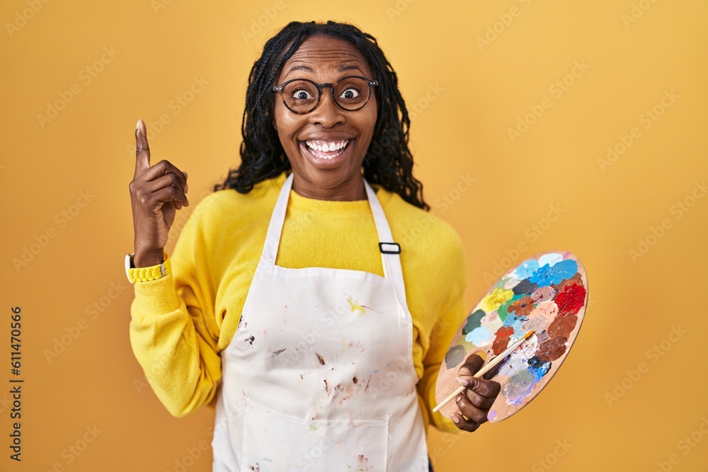 Poster african woman holding painter palette smiling amazed and surprised and pointing up with fingers and 