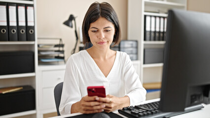 Young beautiful hispanic woman business worker using smartphone working at office