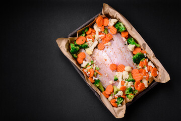 Raw sea bass fish fillet with salt, spices and vegetables in a baking dish