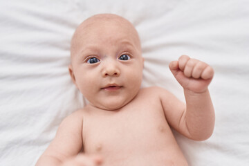 Adorable caucasian baby lying on bed at bedroom