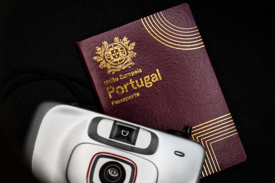 Porto, Portugal - 2023: Portuguese passport with a gray analog camera on a black background.