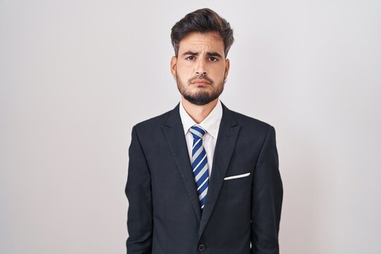 Young hispanic man with tattoos wearing business suit and tie depressed and worry for distress, crying angry and afraid. sad expression.