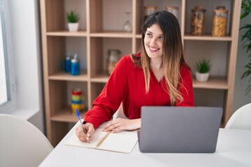 Fototapeta premium Young hispanic woman studying sitting on table at home
