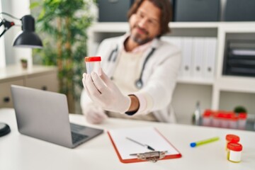 Middle age man doctor holding empty test tube at clinic