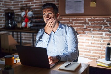 Fototapeta na wymiar Hispanic man with beard working at the office at night bored yawning tired covering mouth with hand. restless and sleepiness.