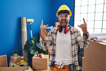Young hispanic man with beard working at home renovation shouting with crazy expression doing rock...