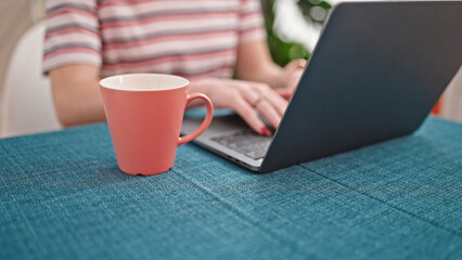 Young blonde woman using laptop at dinning room