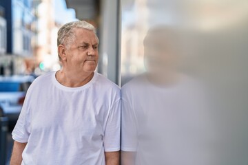 Middle age grey-haired man looking to the side with relaxed expression at street