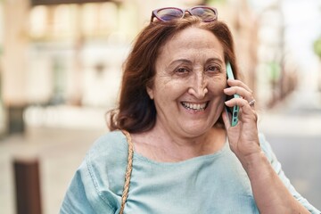 Senior woman smiling confident talking on the smartphone at street