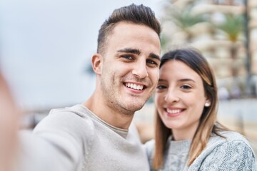 Man and woman couple hugging each other make selfie by camera at seaside