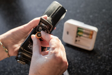 A woman inserts batteries into a camera flash to take pictures
