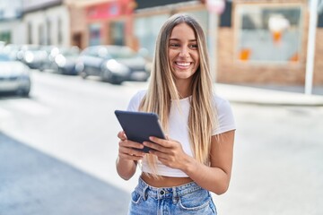 Young beautiful hispanic woman smiling confident using touchpad at street