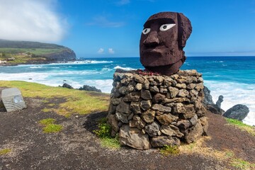 Polynesian Idol Statue Face Head with White Eyes at Rock Platform.  Pacific Ocean Beach Skyline, Easter Island Waterfront, Hanga Roa Chile Background