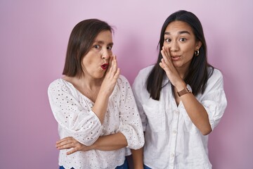 Hispanic mother and daughter together hand on mouth telling secret rumor, whispering malicious talk...