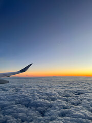 Fototapeta na wymiar Airplane flying over the clouds during sunset
