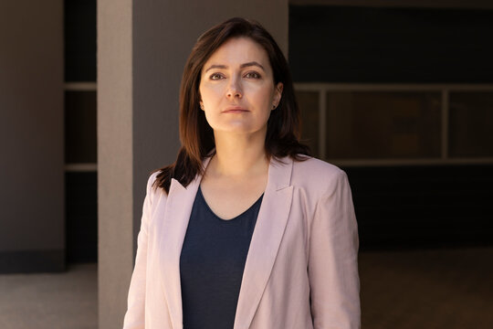 Portrait Confident Mature 40 yo Beautiful Woman, Professional. Intelligent Caucasian Burnette Female With Brown Eyes Looks At Camera, Wears Pink Jackets, Blue Shirt. Horizontal Plane Business Concept