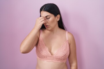 Young hispanic woman wearing pink bra tired rubbing nose and eyes feeling fatigue and headache....