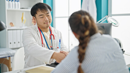 Man and woman doctor and patient shake hands speaking at clinic