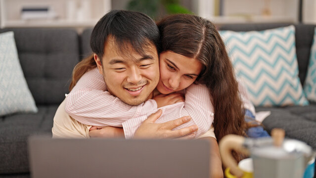 Man and woman couple using laptop hugging each other at home