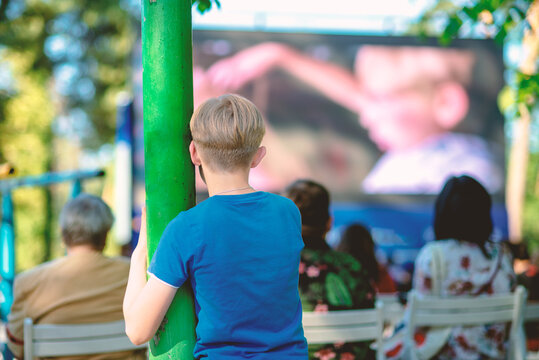 The Boy At The Summer Cinema Is Watching A Movie On The Big Screen.