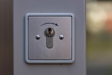Outside pole electronic door opener with an arrow showing the direction of turning the key. Keyhole automated unlocking concept.