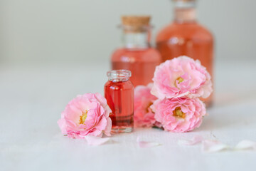 Composition with pure natural organic rose essential oil in glass bottle, luxury perfumery ingredient for premium fragrance, skin care products, anti-age beauty treatment. Fresh flowers