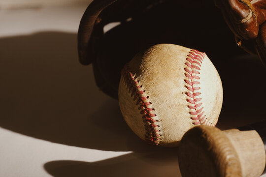 Old sports pastime concept with used dirty ball and baseball glove closeup with worn texture of vintage equipment.