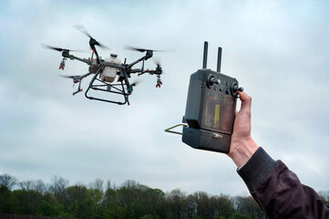Male farmer hands hold the remote control of an agricultural sprayer drone