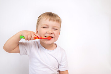 Child with a toothbrush on a white background brushes his teeth and smiles close-up, the concept of caring for children's milk teeth, personal hygiene procedure.