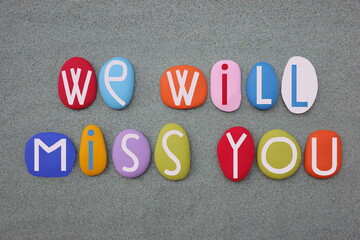 We will miss you, creative message composed with hand painted stone letters over green sand