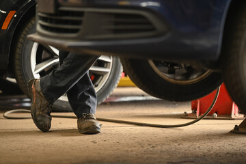 Fototapeta na wymiar male auto mechanic with legs crossed while working on car repair