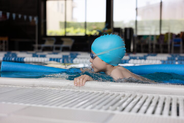 Close up boy swimmer o school boy learning how to swim in a pool wearing in swimming cap and goggles