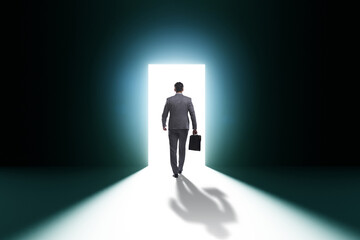 Businessman entering backlit door in escape concept