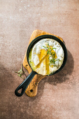 Oven baked camembert cheese with rosemary leaves and raspberry. Homemade grilled brie on rustic...