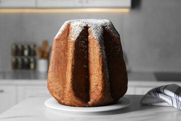 Delicious Pandoro cake decorated with powdered sugar on white table in kitchen. Traditional Italian...