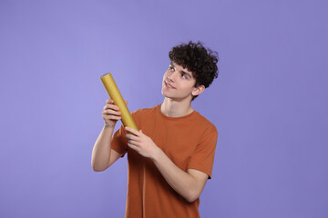 Teenage boy with party popper on violet background